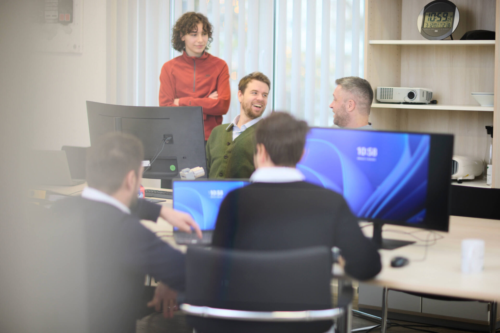 Mehrere Trinidat-Mitarbeiter sitzen und stehen um einen Konferenztisch in einem modernen Büro und besprechen anstehende Projekte.